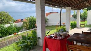 a table with a red table cloth on a patio at CAMA & CAFÉ BED & BREAKFAST HOSPEDARIA MORRO BRANCO 3 MIN A PÉ DAS FALÉSIAs 2 QUADRAS DA PRAIA 1 QUADRA DO MIRANTE & FEIRINHA in Beberibe +73 photos
