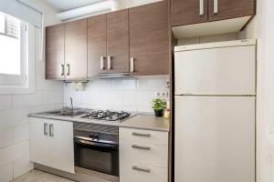 eine Küche mit Holzschränken und einem weißen Kühlschrank in der Unterkunft Sagrada Familia- Emblematic and Charming Catalan Home in Barcelona
