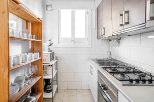 eine weiße Küche mit einer Spüle und einem Herd in der Unterkunft Sagrada Familia- Emblematic and Charming Catalan Home in Barcelona
