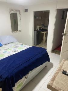 a bedroom with a bed with a blue blanket on it at Habitación independiente cerca al mar. in Puerto Salgar +1 photo