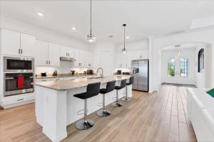 una cocina blanca con una gran isla con taburetes de bar en KGC25240, en Burnt Store Marina