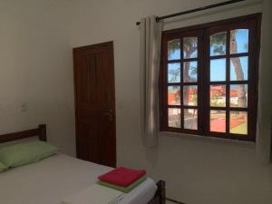 a bedroom with a bed and a window at Chalés de Morro Branco in Beberibe