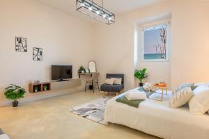 a white living room with a couch and a tv at Seaside Apartment Near St Nicholas Basilica in Bari