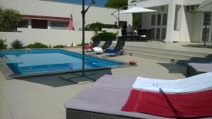 a swimming pool in a yard with chairs and a house at Apartment Markle in Banjol
