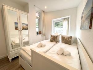 ein großes weißes Bett in einem Zimmer mit Spiegel in der Unterkunft Haus Nordseebrandung FeWo 3 in Cuxhaven