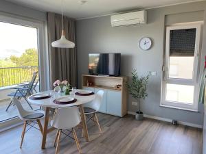 a dining room with a table and chairs and a tv at Vila Primorka-Apartmani Lavanda in Šilo