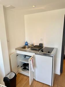 a small kitchen with a stove and a sink at Studio Cosy - Proche MEETT 300m in Cornebarrieu +5 photos