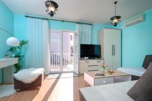 a living room with blue walls and a television at Apartments Bodlovic - ZF Hvar in Hvar