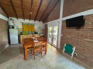 a living room with a wooden table and a brick wall at Cabaña Atardecer del Rio in Mina Clavero
