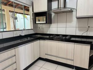 a kitchen with white cabinets and black counter tops at casa próximo ao shopping catuai, eventos vivaro e uem,lebloc in Maringá