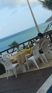 a woman sitting at a table near the ocean at Flat Pé na areia in Natal