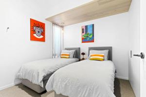 格罗夫海洋Mod House Ocean Grove- Walk to the shops, cafes, beach and park! Brand new luxury apartment in gated complex的卧室设有2张床和白色的墙壁。