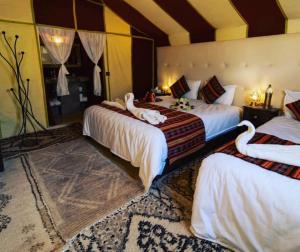 two beds with swans on them in a room at Private Luxury Camp in Merzouga +38 photos