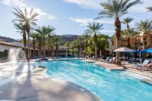 a large swimming pool with palm trees and a fountain at Luxury 1BR Suite Living Room, Patio, Fp & Kitchen, 12 pools -Legacy Villas in La Quinta