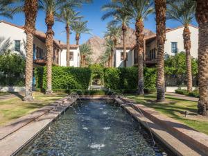 a house with a pond in front of palm trees at Luxury 1BR Suite Living Room, Patio, Fp & Kitchen, 12 pools -Legacy Villas in La Quinta