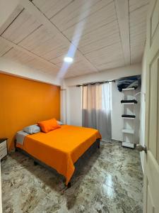a bedroom with a bed with an orange blanket at El guadual apartahotel in Salento