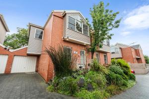 a red brick house with a white garage at Osprey 9 in Queenscliff