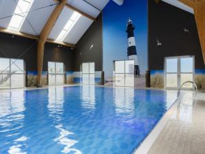 a swimming pool with a lighthouse in the background at Resort Villa Steps to Sand in Nieuwvliet