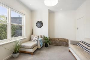a living room with a couch and a clock on the wall at Perfect Family Getaway in Point Lonsdale