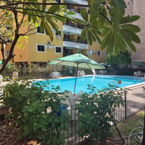 a swimming pool with an umbrella next to a building at Apartamento em Recife in Recife +3 photos