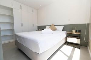a bedroom with a large white bed and white cabinets at Ventura Carmelitas in Asuncion +14 photos