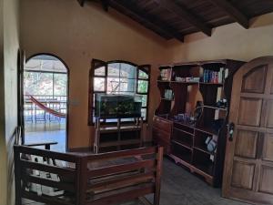 a living room with a tv and a wooden door at Osa House - Drake Bay in Drake