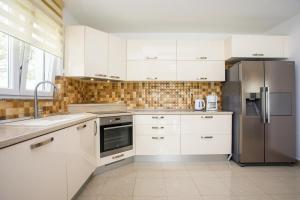 a kitchen with white cabinets and a stainless steel refrigerator at Family friendly house with a swimming pool Srinjine, Split - 23950 in Srinjine