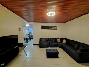 a living room with a black couch and a flat screen tv at Isabella House, Beautiful views of the mountains in Matagalpa