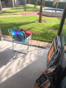 a chair sitting on a porch next to a tv at Bangalô Grandes Lagos in Santa Clara dʼOeste