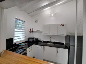 a kitchen with white cabinets and a black counter top at Villa SAINT BARTHELEMY in Saint-François