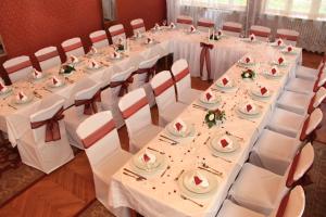 einen langen Tisch mit weißen Tischdecken und weißen Stühlen in der Unterkunft Hotel Ózd in Ózd