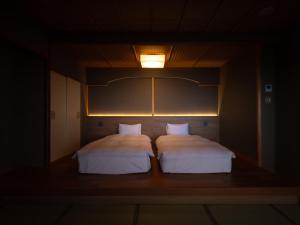 a bedroom with two beds and a light on the wall at Kaiyutei in Kawazu