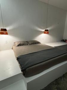 a bed in a room with two lights on it at Casa Woody in Santo Amaro