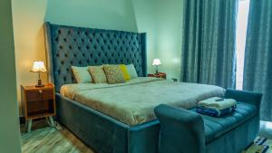 a bedroom with a large bed with a blue headboard at Serene Homes 03 in Kampala