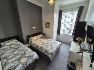 a hotel room with two beds and a desk at Miricia Guest House in Scarborough