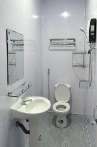 a white bathroom with a toilet and a sink at Ngôi Nhà Hạnh Phúc in Plei Kêp
