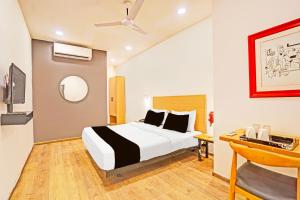 ラクナウにあるSuper Townhouse Mukut Bazarのベッドと机があるホテルの部屋