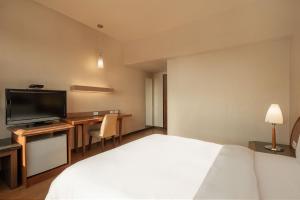 a hotel room with a bed and a desk with a television at Kindness Hotel - Wu Jia in Kaohsiung +17 photos