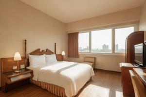 a hotel room with a bed and a television at Kindness Hotel - Wu Jia in Kaohsiung