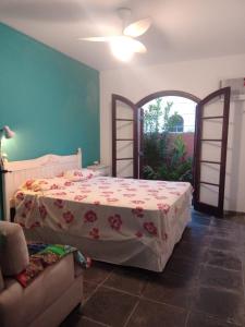 a bedroom with a bed and a couch in a room at Casa Praia Jardim Acapulco in Guarujá
