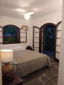 a bedroom with a bed and two open windows at Casa Praia Jardim Acapulco in Guarujá