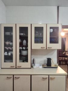 a kitchen with white cabinets with dishes in it at Casa Praia Jardim Acapulco in Guarujá +15 photos