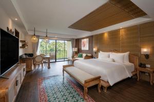 a bedroom with a large bed and a living room at Metland Venya Ubud in Ubud