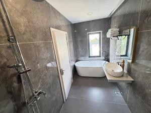 a bathroom with a bath tub and a sink at Times Hotel in Trảng Bàng