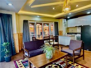 a living room with a table and chairs and a kitchen at Appa Apartments in Thimphu