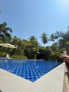 a swimming pool in a resort with palm trees at The Leaf Bankrut - Cosy Cottage in Ban Krut
