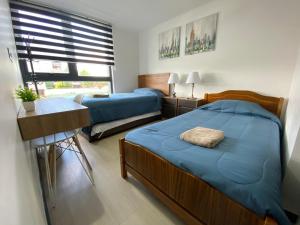 巴拉斯港Dpto costero vista al lago, piscina y jacuzzi的一间卧室，有两张床、一张书桌和一扇窗户