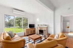 een woonkamer met twee banken en een open haard bij Springs Beach House in Point Lonsdale