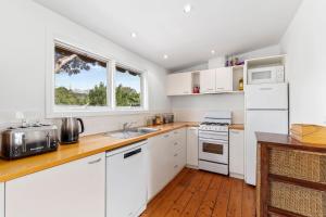 een keuken met witte kasten, een gootsteen en een raam bij Springs Beach House in Point Lonsdale