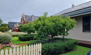 a white fence in front of a house with a tree at The Manse in Queenscliff